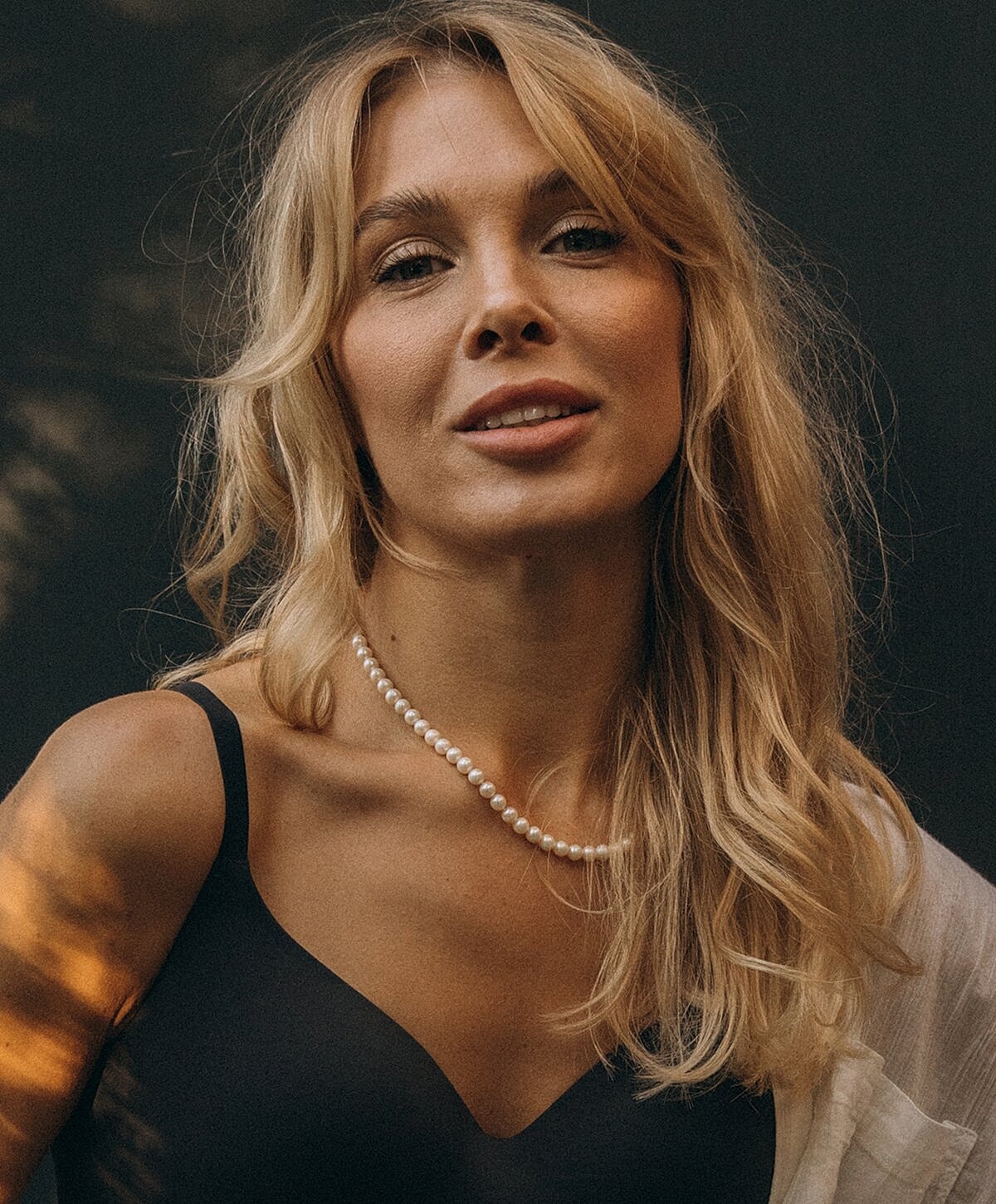 Model posing in neutral-colored lingerie against backdrop.