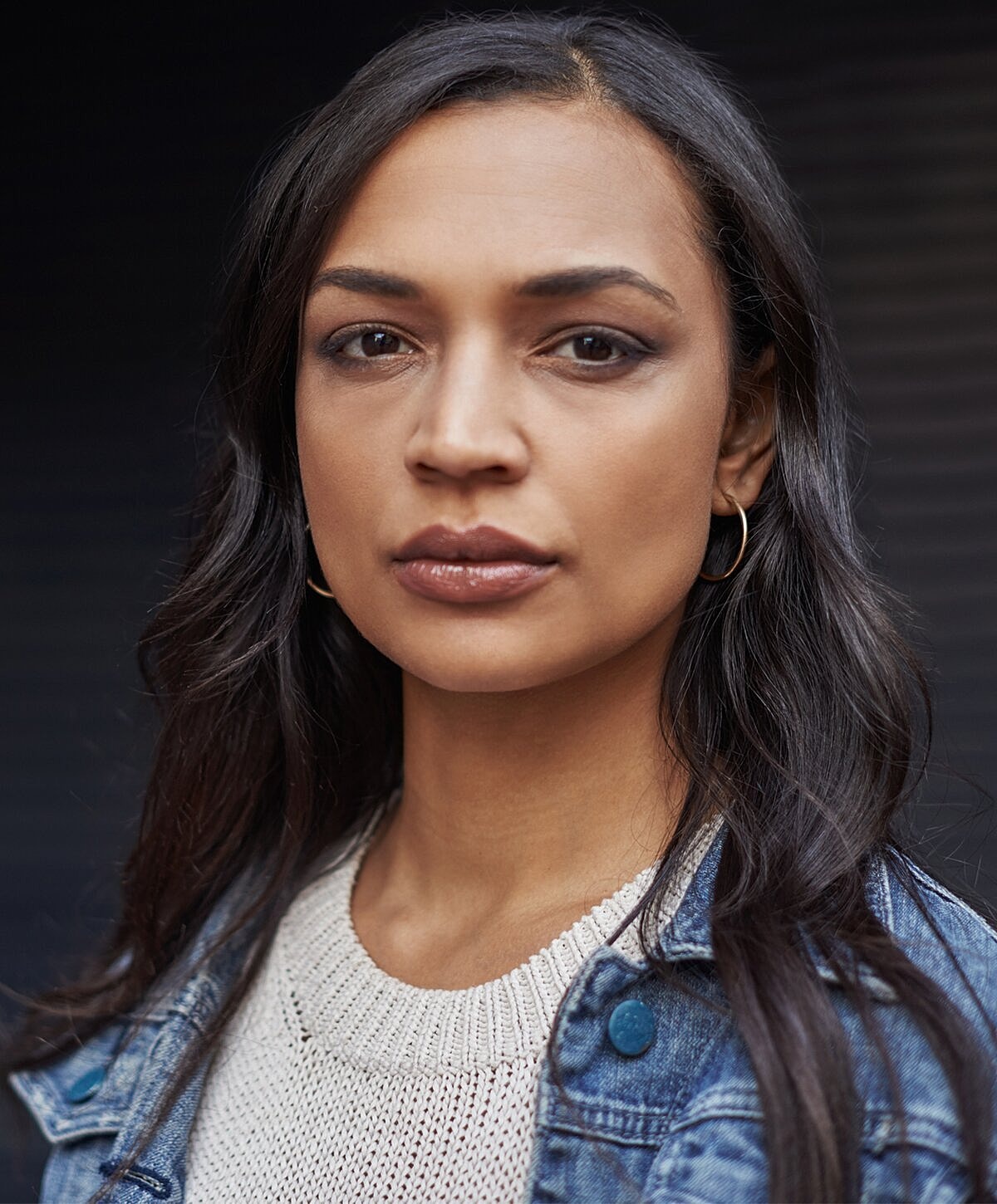 Model striking a pose against a textured wall.