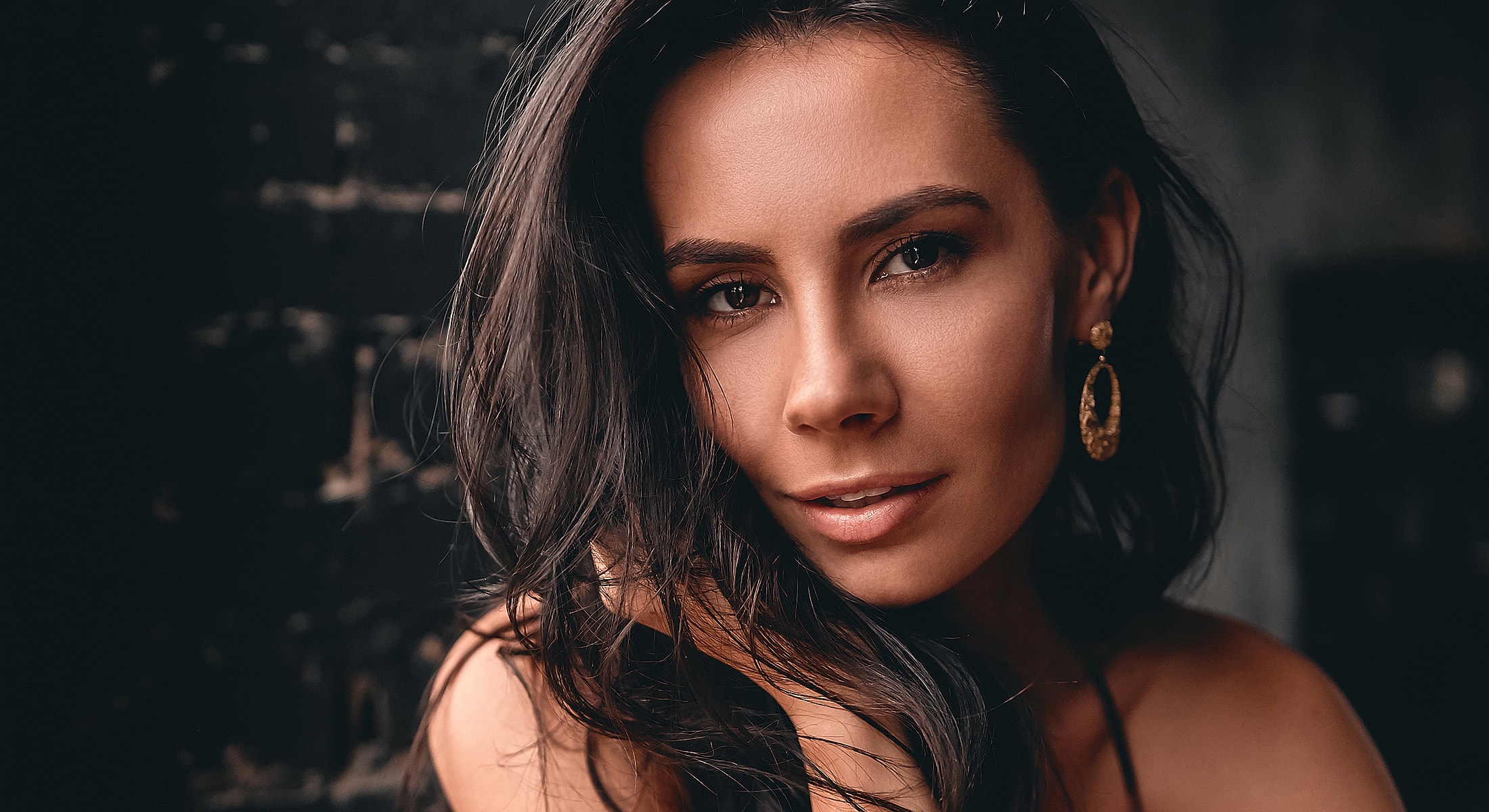 Portrait of a woman with dark hair and earrings.