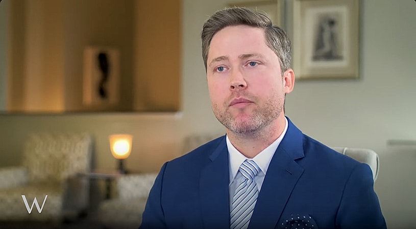 Man in suit speaking in an office setting.