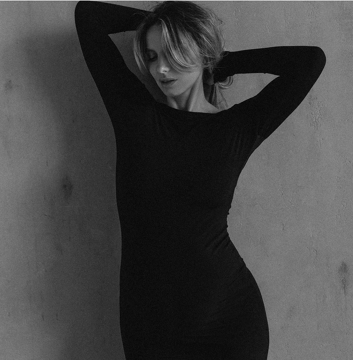 Model striking a pose against a textured wall.