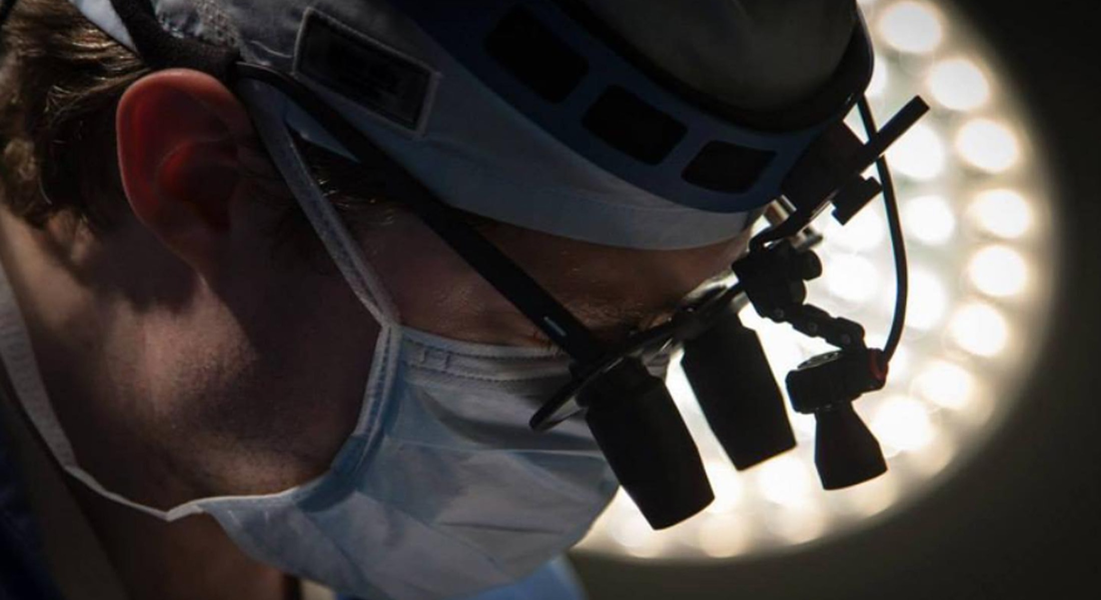 Surgeon focused under bright operating room lights.